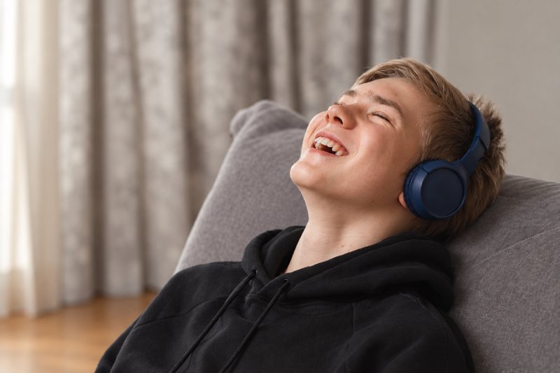 Un adolescent, casque sur les oreilles, rit pendant une séance d’écoute